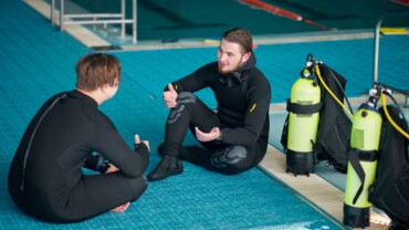 Divers in scuba gear leisures after dive lesson