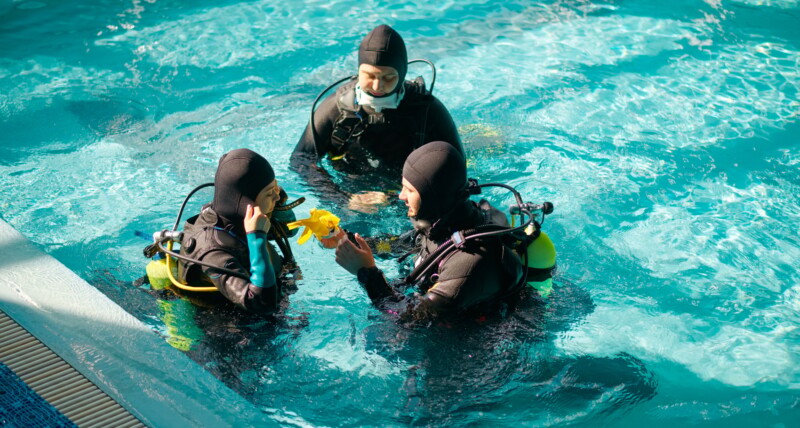 Instructor and divers in aqualungs, dive course