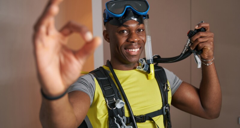 Joyful scuba diver in room showing ok gesture