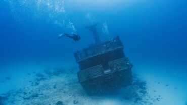 scuba diver swimming into a deep wreck